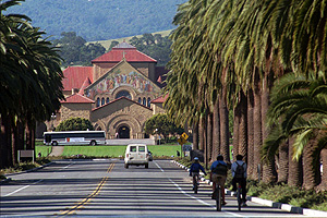 Bike riders and vehicles go down Palm Drive towards the Stanford University campus in Palo Alto, California.